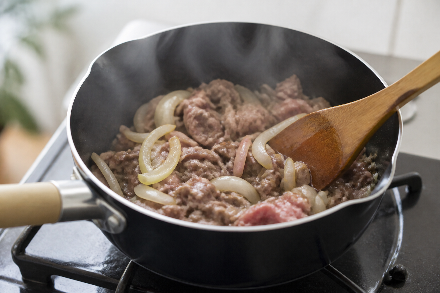 Thinly sliced beef and onions browning in a saucepan for nikujaga