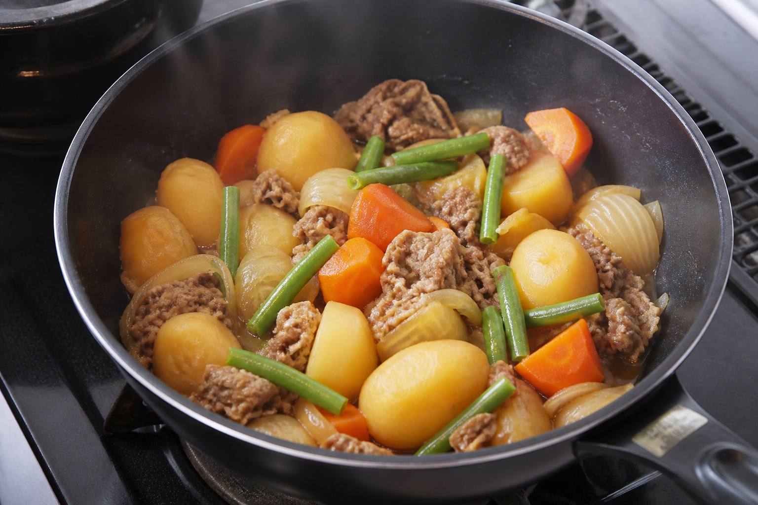 Finished nikujaga resting in the pot with tender potatoes, beef, carrots and green beans