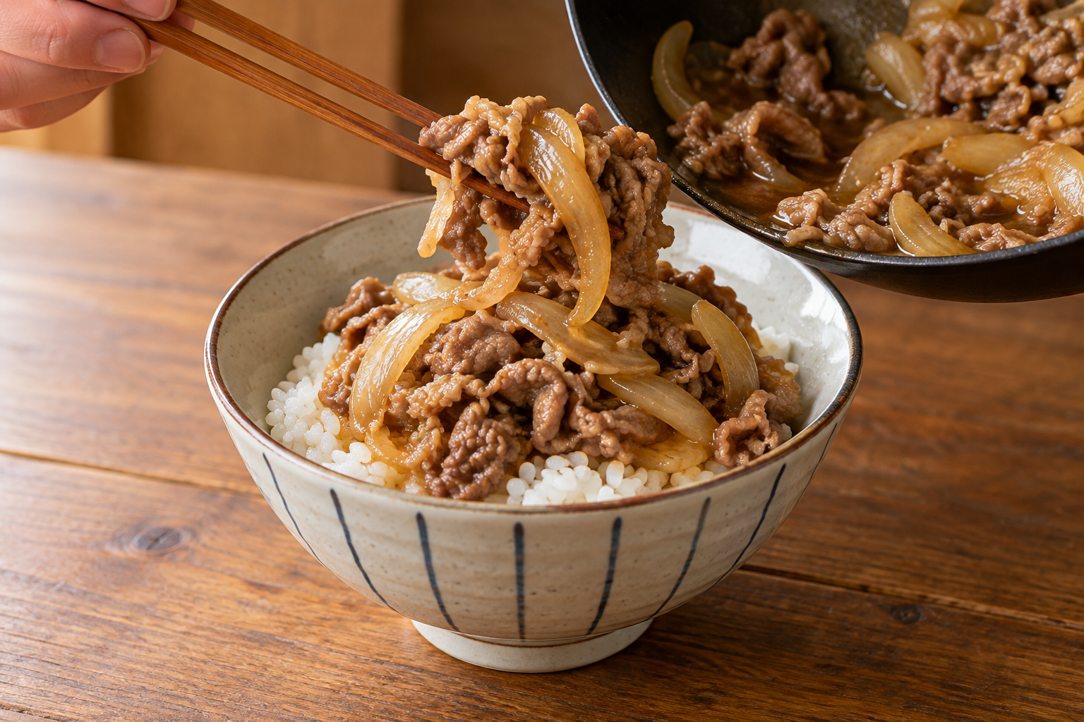Cooked beef and onion being served over Japanese rice in a donburi bowl